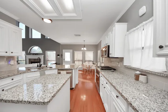 a large kitchen with stainless steel appliances granite countertop a large stove a sink dishwasher and cabinets with wooden floor