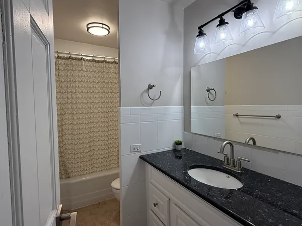 a bathroom with a granite countertop sink a toilet and a mirror