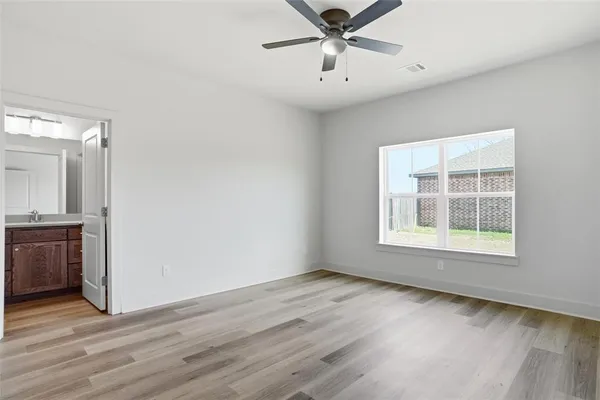 an empty room with wooden floor fan and windows