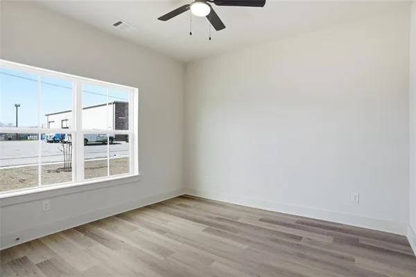 an empty room with wooden floor and windows