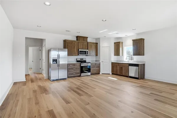 a large kitchen with stainless steel appliances a large counter top a stove and a refrigerator