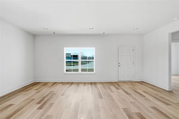a view of an empty room with wooden floor and a window