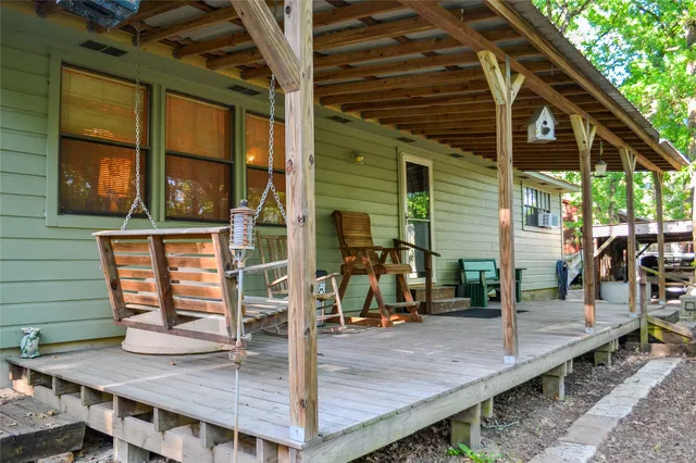 a backyard of a house with table and chairs and large tree