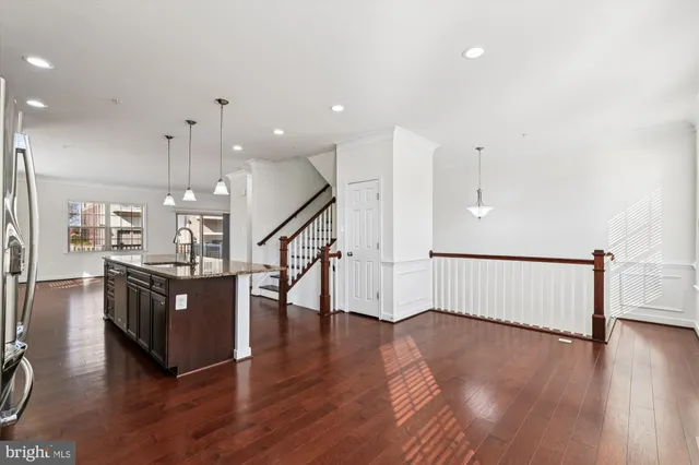 a kitchen with stainless steel appliances granite countertop a refrigerator a sink dishwasher a oven and a dining table with wooden floor