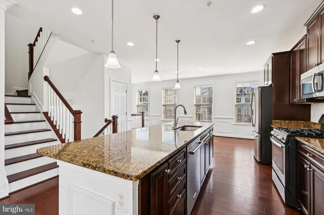 a kitchen with stainless steel appliances granite countertop a refrigerator a stove and a sink with wooden cabinets