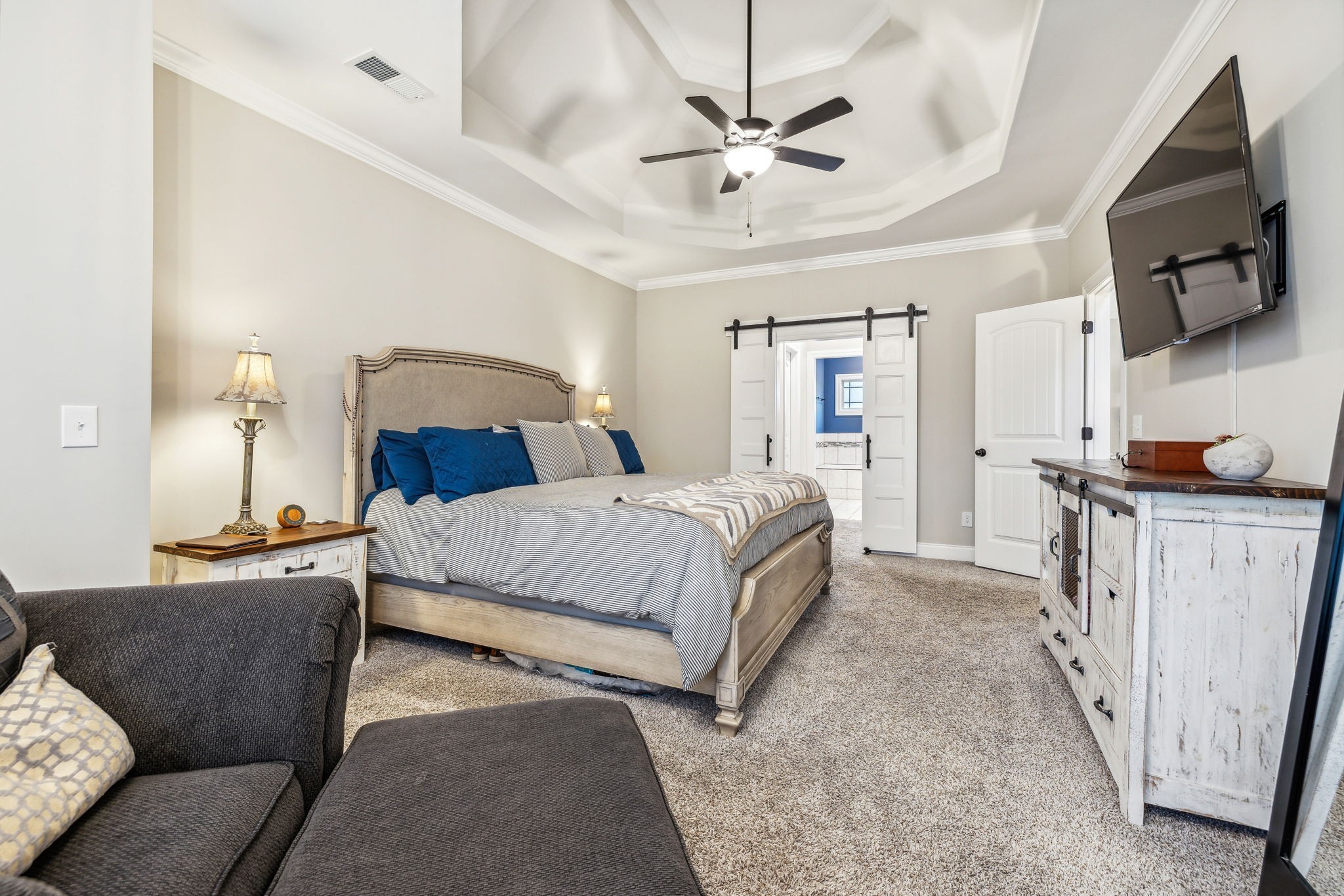 718 Walnut Grove Road Christiana, TN 37037 - Photo 23 of 49 a spacious bedroom with a bed a couch and a flat tv screen on a dresser