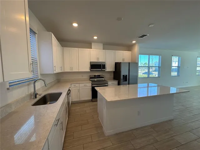 a kitchen with granite countertop a sink a counter top space stainless steel appliances and cabinets