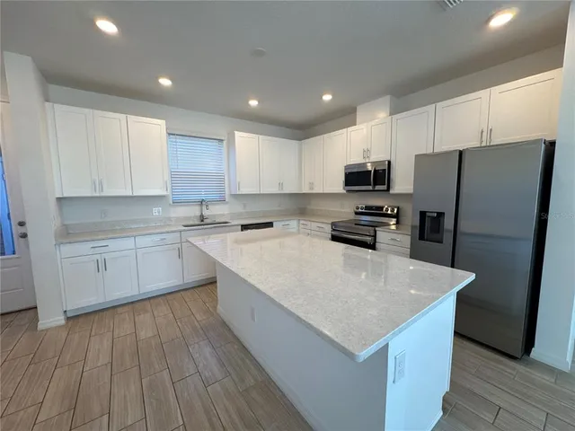 a kitchen with stainless steel appliances a microwave a sink a stove a refrigerator and cabinets