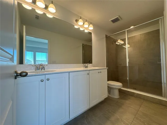 a bathroom with a toilet a sink a shower and mirror