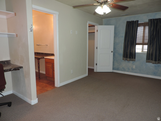 140 North 200 E Street Glenwood, UT 84730 - Photo 28 of 54 Unfurnished bedroom featuring built in study area, dark colored carpet, a walk in closet, ensuite bathroom, and a ceiling fan
