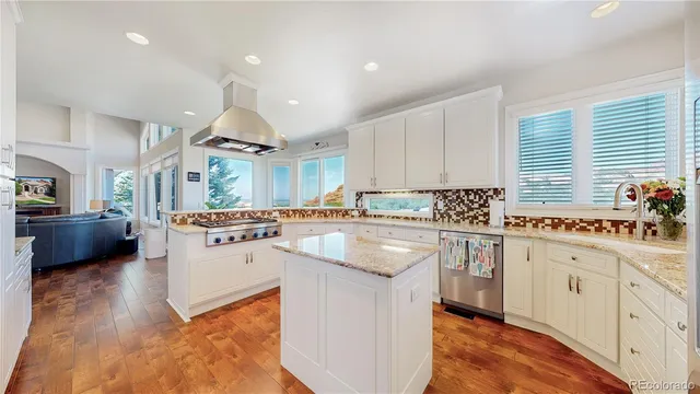a kitchen with stainless steel appliances granite countertop a sink a stove a refrigerator cabinets and living room view