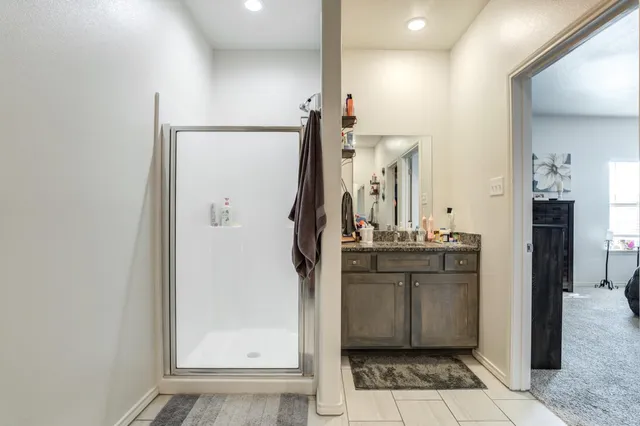 a bathroom with a granite countertop sink a mirror and a shower