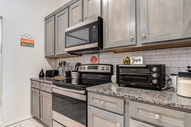 a kitchen with granite countertop a stove and a microwave