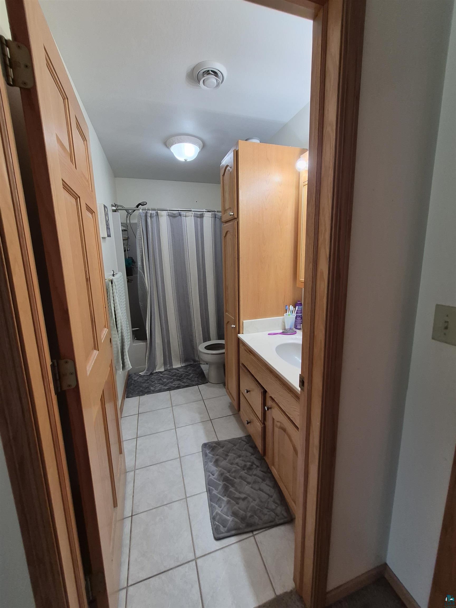 3020 East 8th Street Superior, WI 54880 - Photo 28 of 37 Wood-finish panel doors and trim, tile flooring, and a single vanity with wood-finish cabinetry