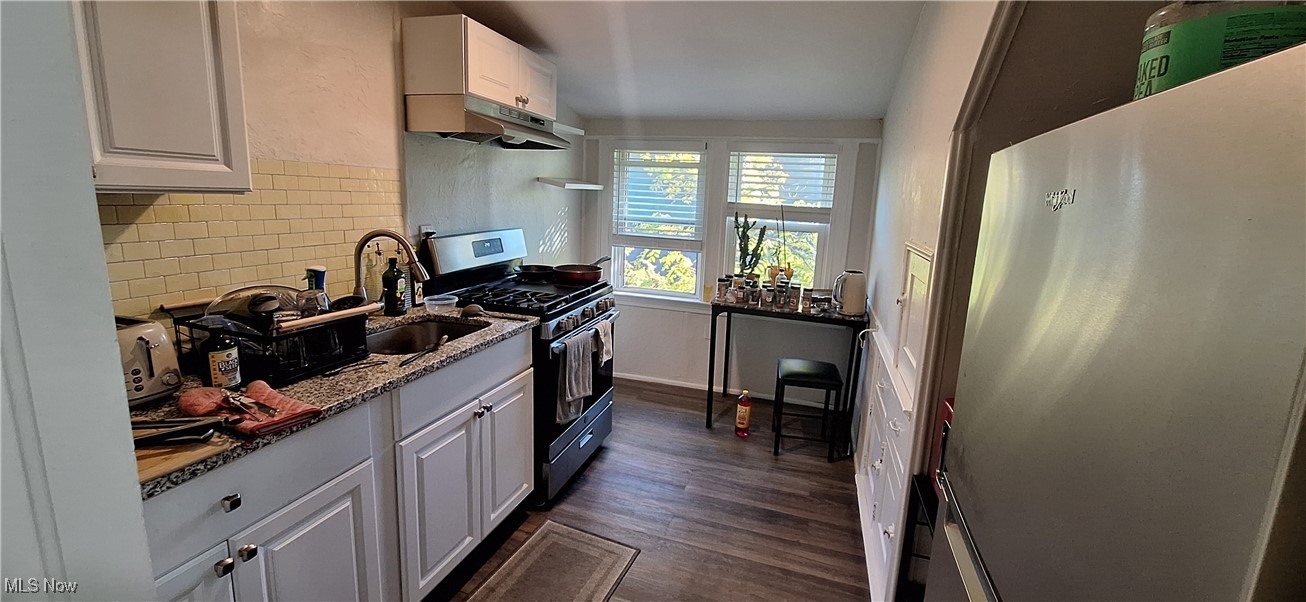 1477 Genesee Road South Euclid, OH 44121 - Photo 15 of 26 Kitchen featuring white cabinets, appliances with stainless steel finishes, light stone countertops, under cabinet range hood, and dark wood-type flooring