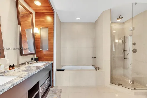 a bathroom with a granite countertop double vanity sink mirror and shower