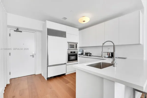 a kitchen with a refrigerator sink and white cabinets