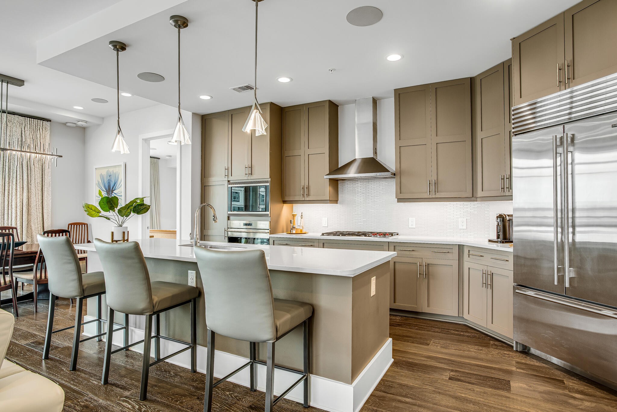 a kitchen with stainless steel appliances granite countertop a sink a stove a refrigerator and island with wooden floor