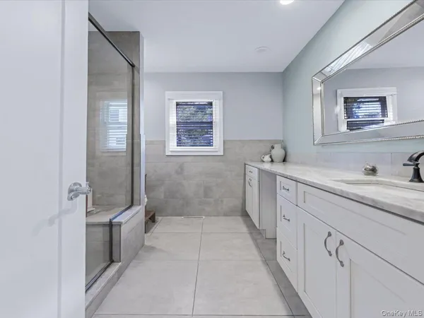 a spacious bathroom with a double vanity sink a mirror and a shower