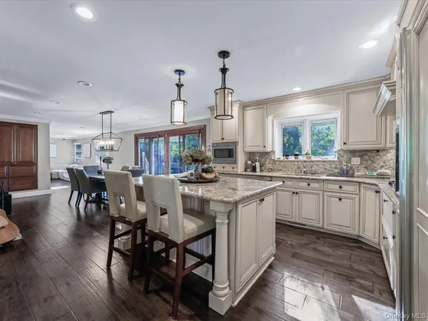 a kitchen with kitchen island granite countertop a table chairs sink and cabinets