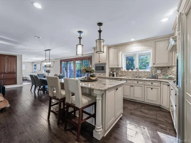 a kitchen with kitchen island granite countertop a table chairs sink and cabinets