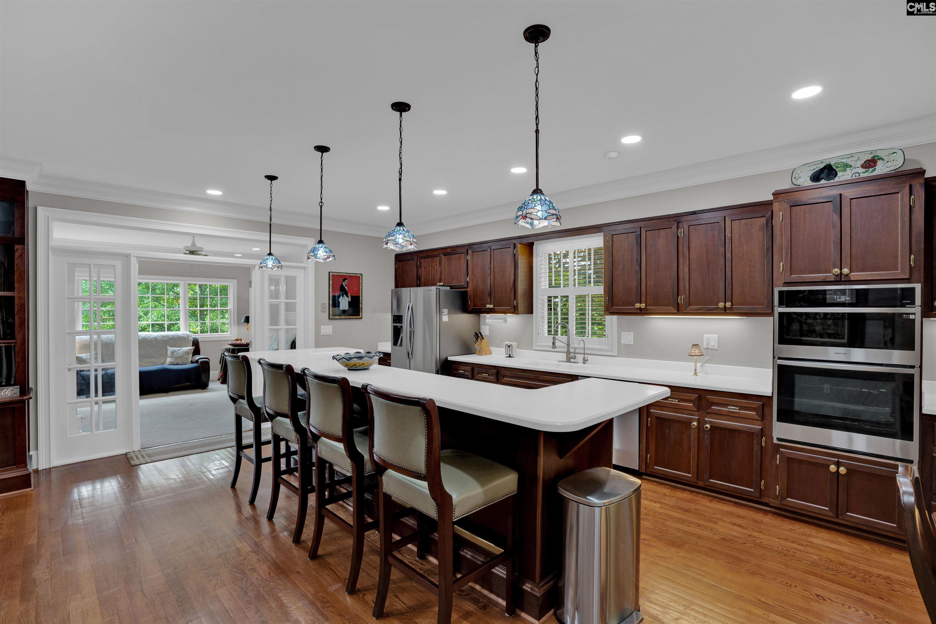 1101 Ellett Road Chapin, SC 29036 - Photo 7 of 24 a kitchen with stainless steel appliances granite countertop a stove a refrigerator a kitchen island a dining table and chairs with wooden floor
