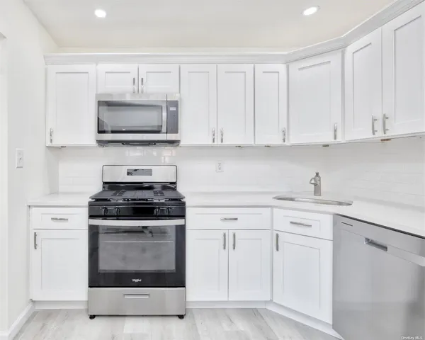 a kitchen with white cabinets and stainless steel appliances