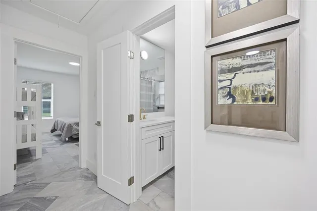 a view of a hallway with wooden floor and a bathroom