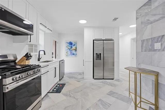 a kitchen with stainless steel appliances granite countertop a refrigerator and a stove top oven