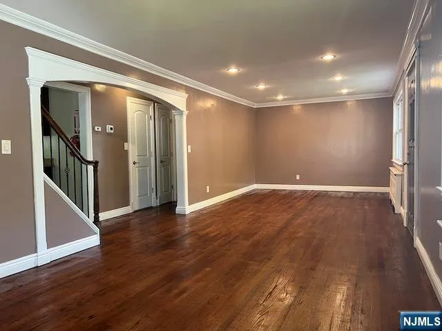 an empty room with wooden floor and a hallway