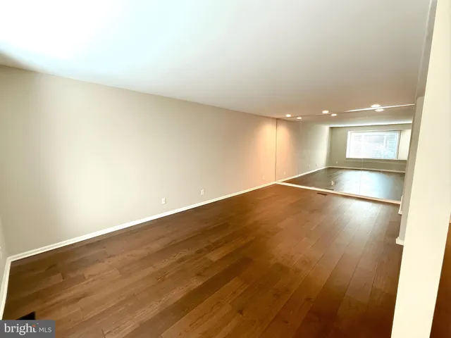 an empty room with wooden floor and kitchen