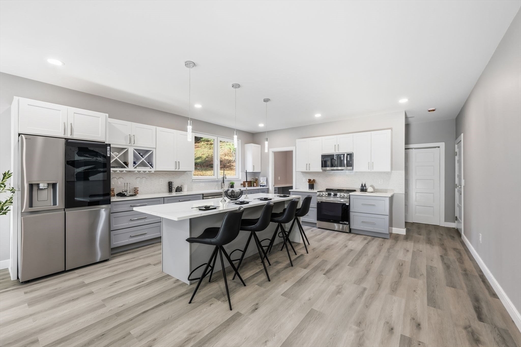 287 Whitney Avenue Holyoke, MA 01040 - Photo 11 of 40 a kitchen with a table chairs refrigerator and microwave