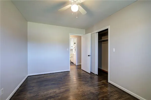 a view of an empty room with wooden floor and a ceiling fan