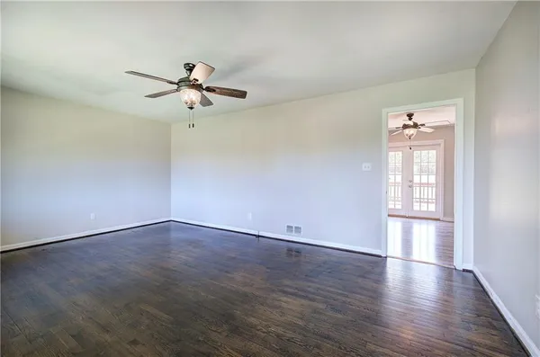 an empty room with wooden floor ceiling fan and windows
