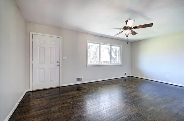 a view of an empty room with wooden floor and a window