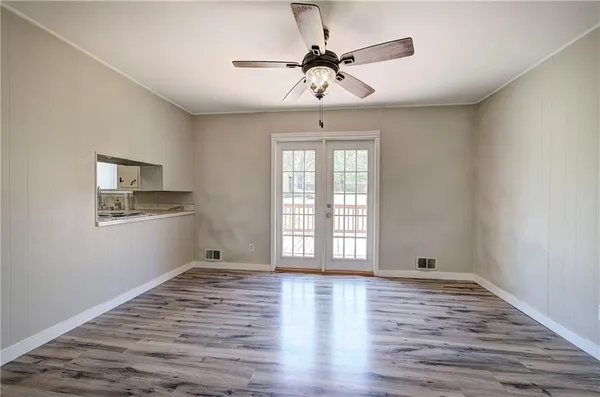 a view of empty room with wooden floor and fan