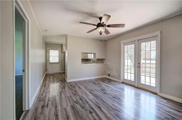an empty room with wooden floor fan and windows