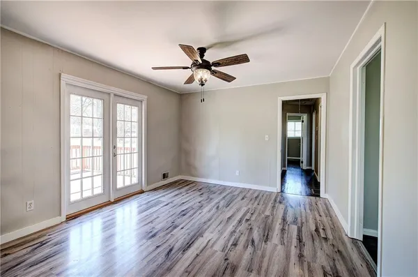 a view of empty room with wooden floor and fan