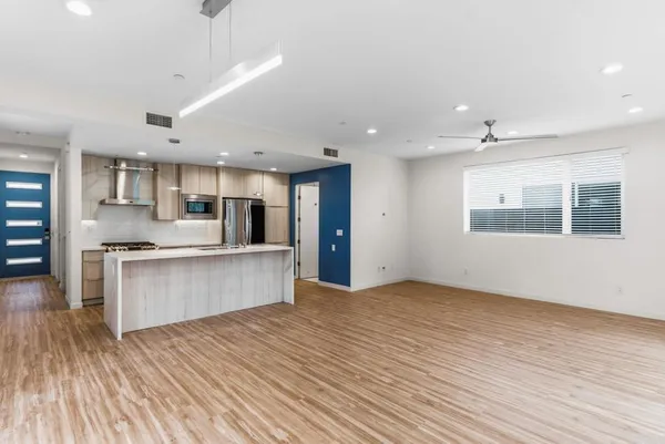 a large kitchen with stainless steel appliances kitchen island a large counter top and a wooden floors