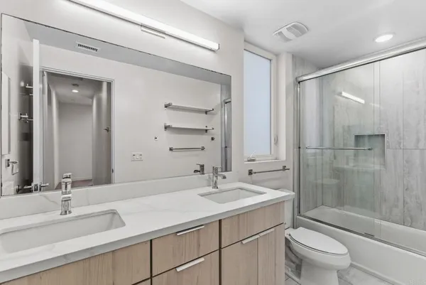 a bathroom with a sink toilet double vanity and shower