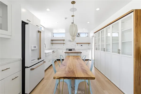 a kitchen with stainless steel appliances granite countertop a refrigerator a oven and white cabinets with wooden floors