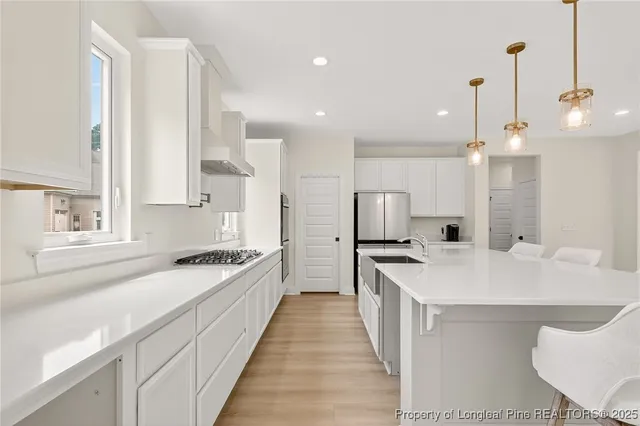 a kitchen with a sink a stove a refrigerator and white cabinets