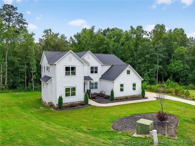 a view of a white house with a yard and sitting area