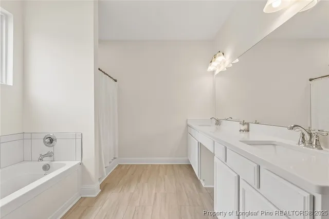 a bathroom with a double vanity sink a mirror and a bathtub
