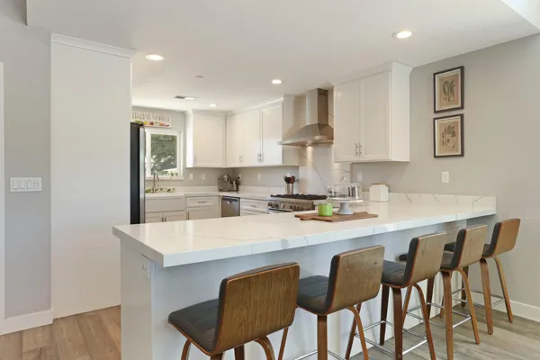 a kitchen with stainless steel appliances granite countertop a table chairs and a refrigerator