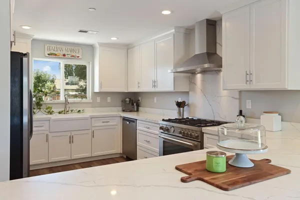 a kitchen with stainless steel appliances kitchen island granite countertop a refrigerator and a sink