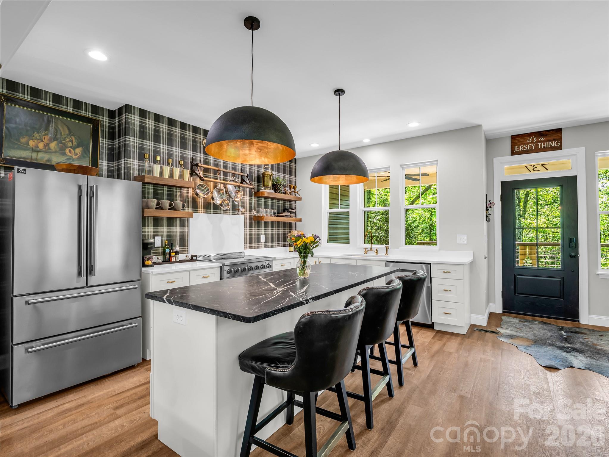 737 Melrose Mountain Road Tryon, NC 28782 - Photo 15 of 42 a kitchen with stainless steel appliances granite countertop a stove a refrigerator a sink a dining table and chairs with wooden floor