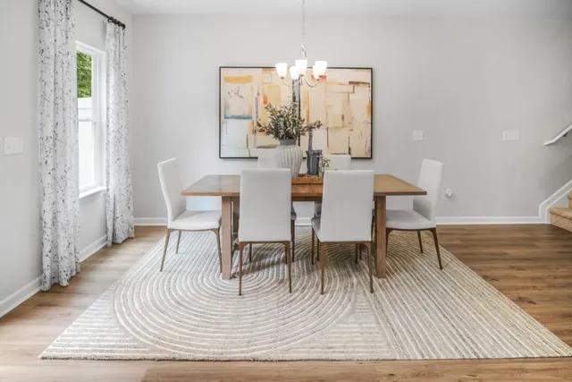 a dining room with wooden floor a glass table and chairs