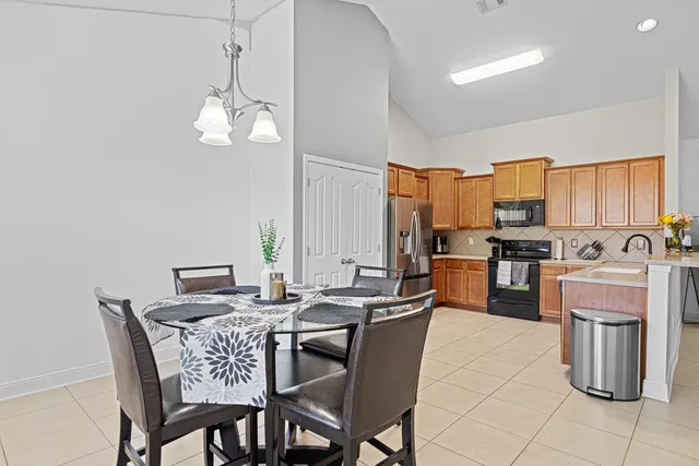 a view of a dining room with furniture a kitchen and chandelier
