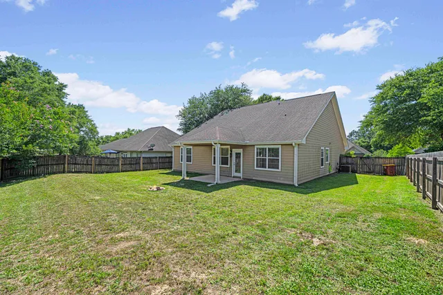 a view of a house with a big yard potted plants and large tree